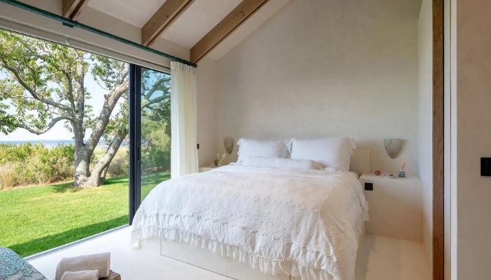 A natural lit bedroom with smart shades that are rolled all the way up.