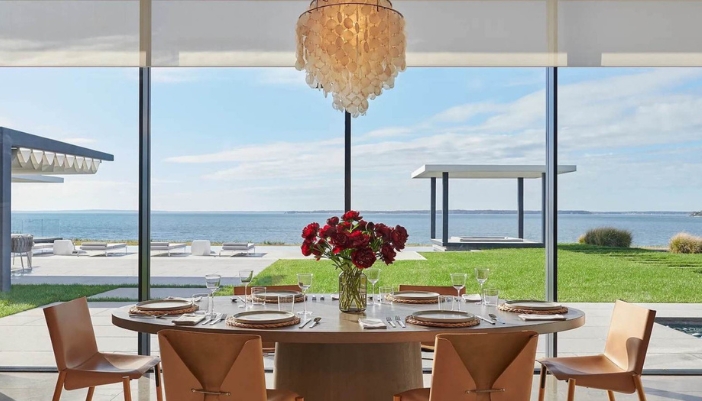 A dining room table in a naturally lit room with shades drawn open.