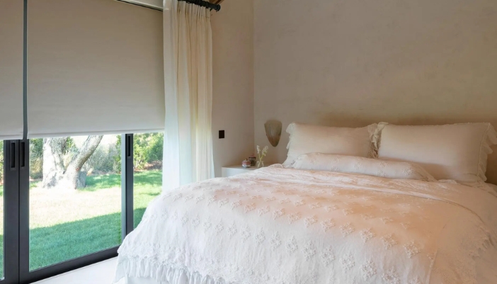 A modern bedroom with all white accents and modern shades.