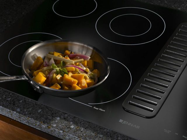 Close view of a JennAir downdraft cooktop pulling steam from a cooking pan