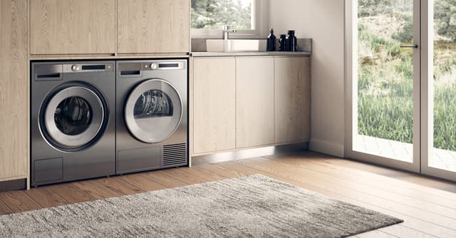 Two open Asko laundry machines next to a dog. Two open Asko laundry machines next to a dog.