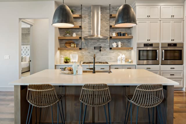 Front view of a modern kitchen with a Bosch cooktop and range hood along with two wall ovens out of frame