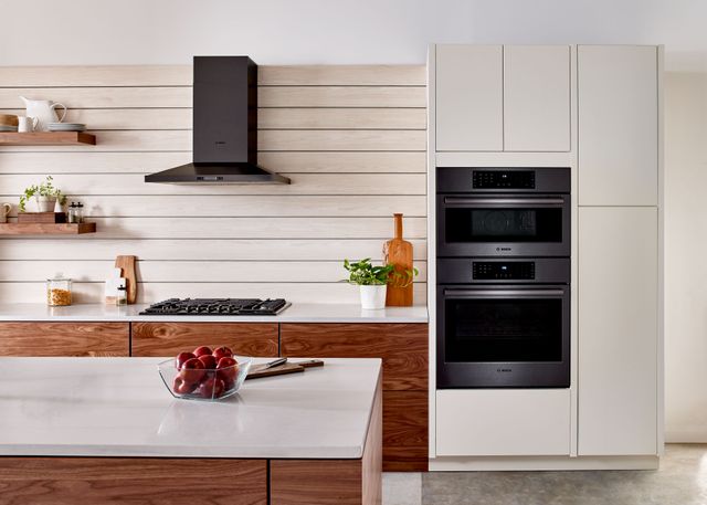 Credit: Bosch Front view of a modern kitchen with a black stainless steel Bosch gas cooktop, rangehood, and double wall oven