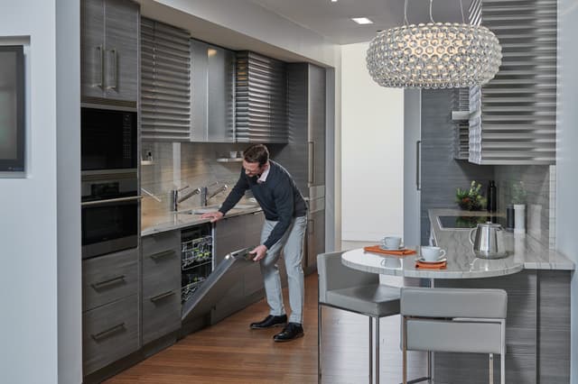 Front view of a man opening a Cove dishwasher Front view of a man opening a Cove dishwasher