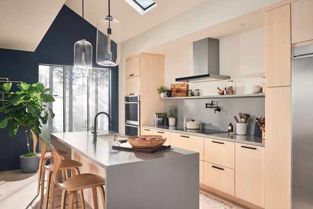 Front view of a modern kitchen with Electrolux appliances, with a wall mount range hood