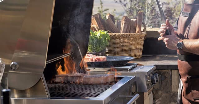 Credit: Kalamazoo Side view of a man cooking on a flame on a grill
