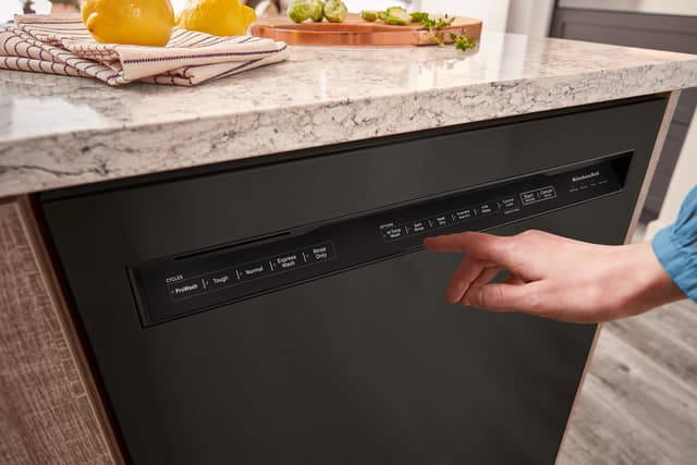 Credit: KitchenAid Front view of a person pressing the feature buttons on their KitchenAid dishwasher
