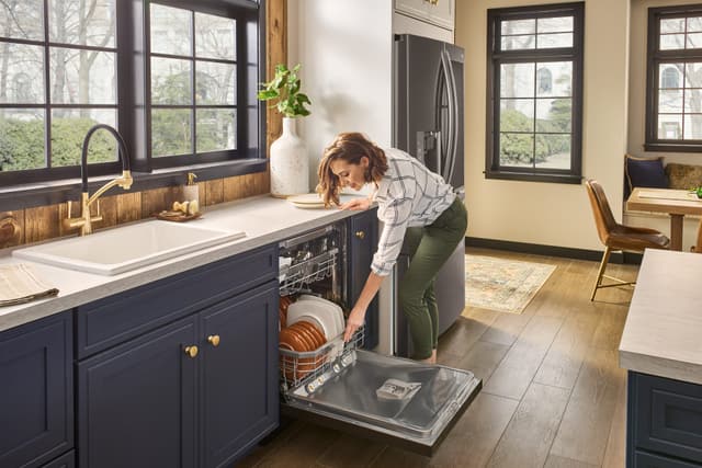 Credit: LG Woman opening her built in LG dishwasher in a modern kitchen