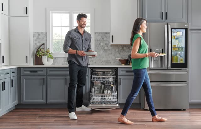 Front view of a couple putting dishes away in their modern kitchen from an LG dishwasher Front view of a couple putting dishes away in their modern kitchen from an LG dishwasher