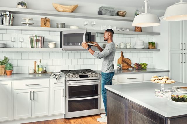 Credit: LG Front view of a modern kitchen with a man using his over the range microwave