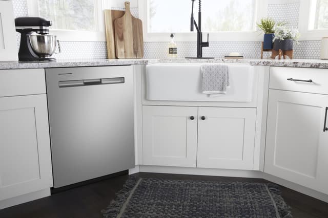Front view of a modern kitchen with a Maytag dishwasher next to a sink Front view of a modern kitchen with a Maytag dishwasher next to a sink
