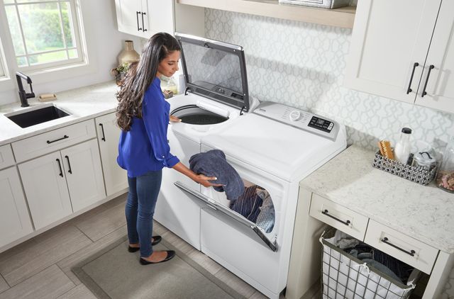Front view of a woman moving clothes from her washer to dryer