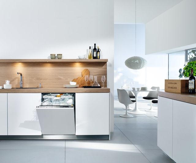 Front view of a modern kitchen with an opened Miele dishwasher