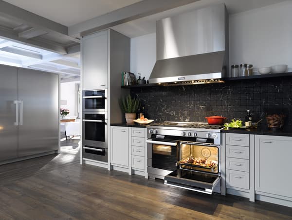 Miele Appliances A 48 inch range, wall mounted range hood, and oven are installed in a modern kitchen