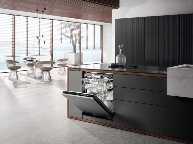 Front view of a modern kitchen with a Miele panel ready dishwasher opened