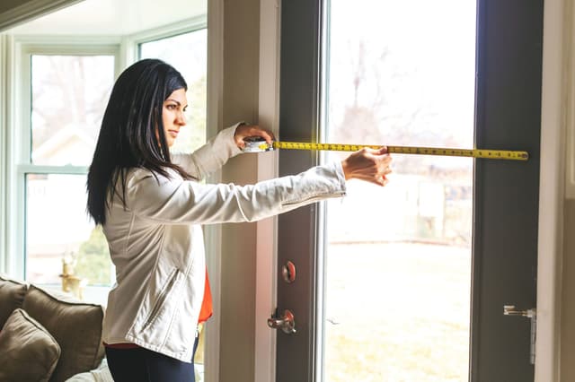 Credit: iStock Front view of a woman measuring her door entrance