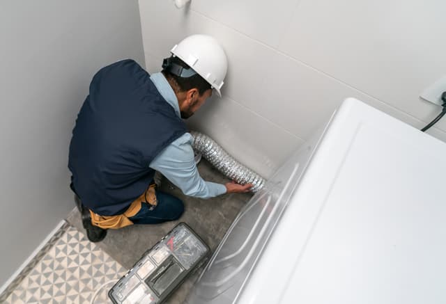 Front view of a man installing a dryer vent