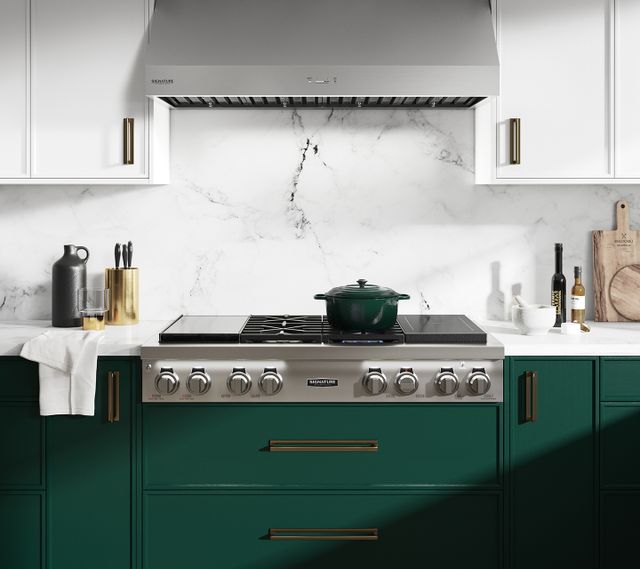 Credit: Monogram Front view of a Monogram gas rangetop and range hood in a modern kitchen