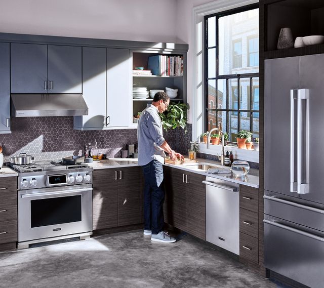 Front view of a modern kitchen with a man cooking with his SKS stainless steel appliances