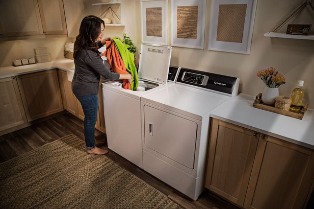 View from behind of a woman loading laundry into her Speed Queen top load washer
