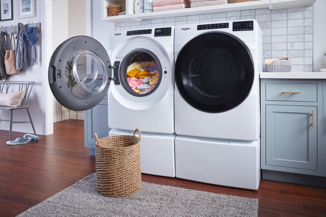 Front view of a modern laundry room with an opened Whirlpool front load washer