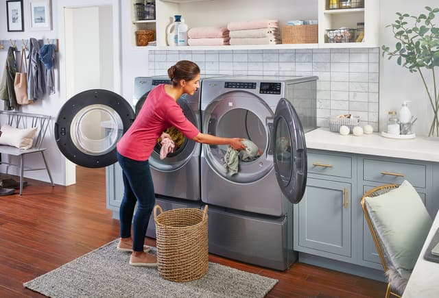 Front view of a woman transferring clothes from her Whirlpool washer to dryer