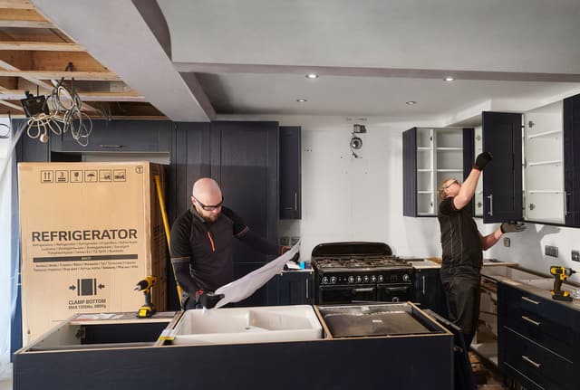 Credit: iStock Front view of two men building a modern kitchen and installing appliances