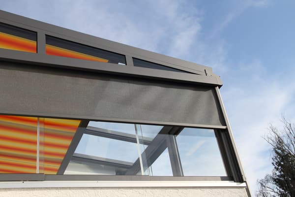 Motorized outdoor shade completely enclosing a patio dining space at sunset