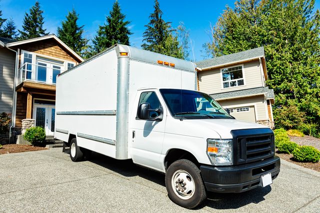 Front view of a white delivery truck in front of a home