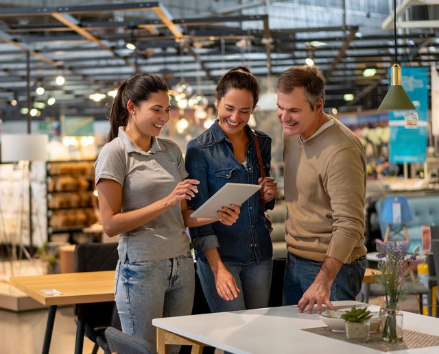 Front view of a couple chatting with a saleswoman in a furniture store and smiling