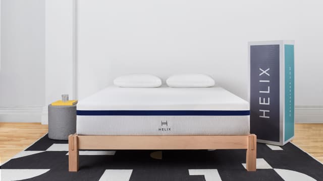 Front view of a modern bedroom with a Helix mattress in a box and the box beside it Front view of a modern bedroom with a Helix mattress in a box and the box beside it