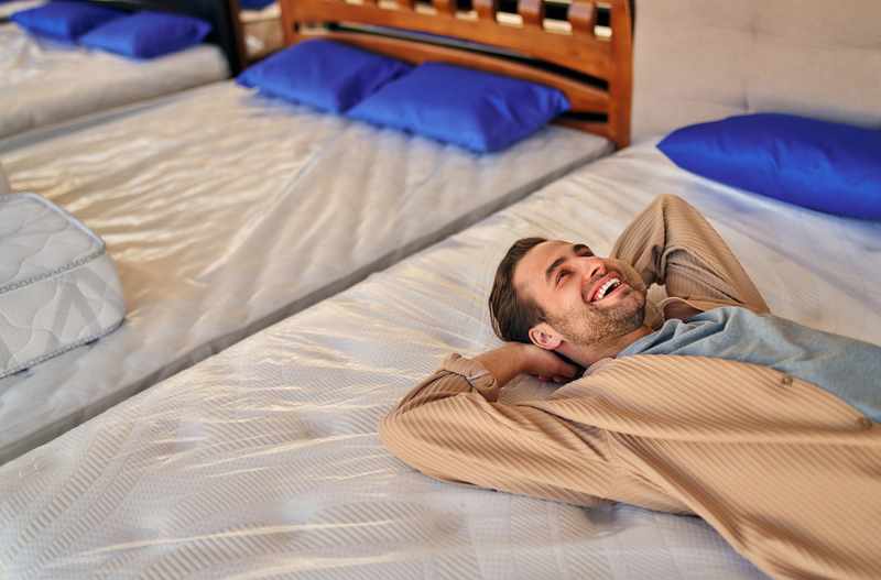 Man smiling, laying on mattress