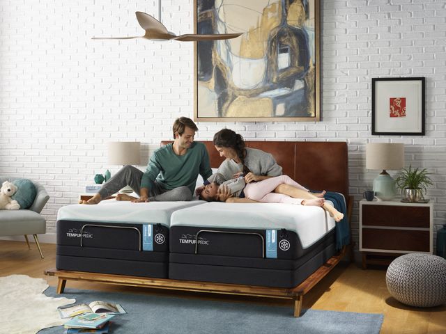 Credit: Tempur-Pedic Front view of a family sitting and smiling on a large Tempur-Pedic Mattress