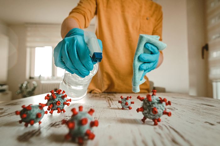 woman in disposable disinfects table with disinfectant and a rag