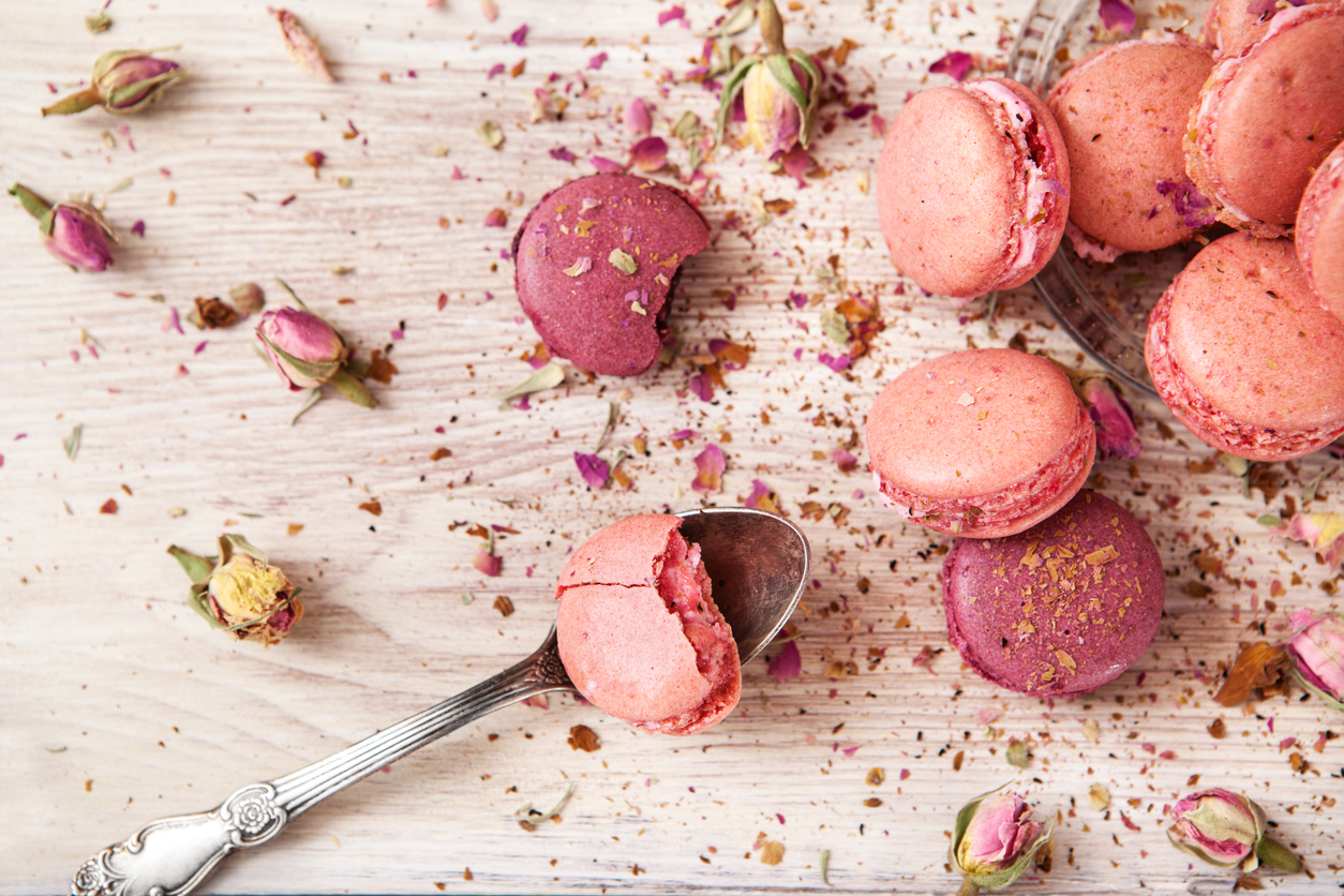 pink macarons and dried rosebuds against a wood background 