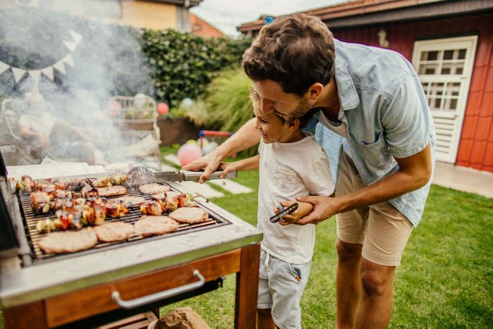 father and son grilling meat during BBQ party