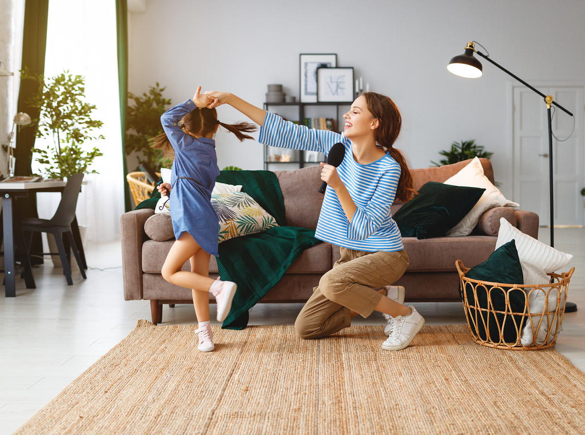 mother and daughter singing and dancing in living room