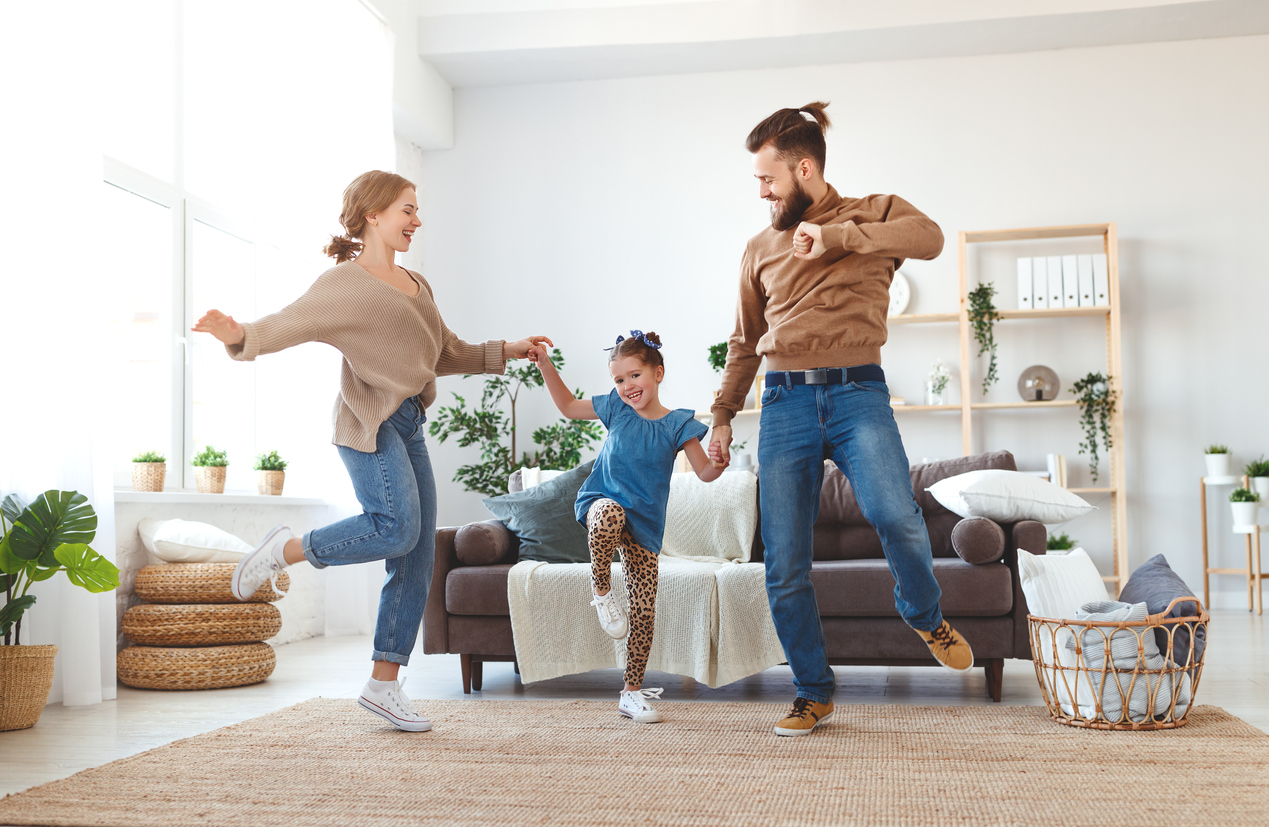 hipster parents and young child dancing in living room