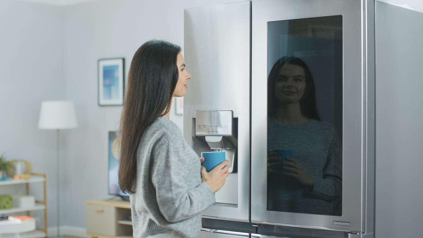 young woman navigates the touchscreen on her smart fridge