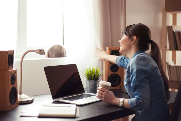 woman working at her modern home office moves curtains to look outside