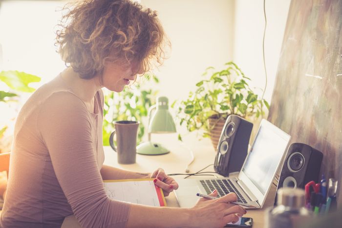 woman is surrounded by potted plants at her desk working from home 