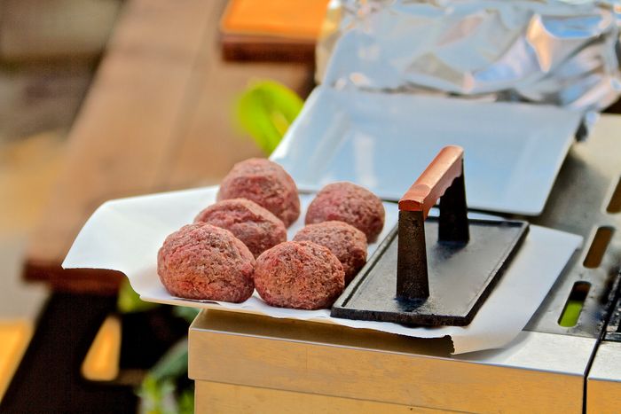 rolled up hamburger meat next to a burger press