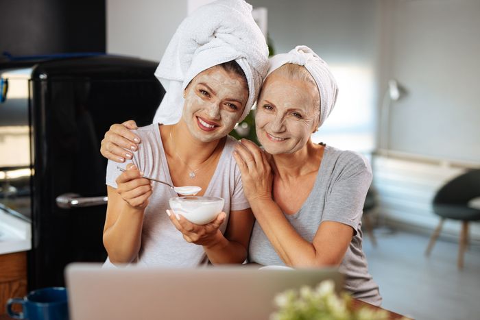 mother and daughter smiling while wearing clay masks