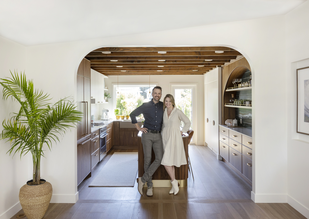 A pair stands happily in the archway of their newly renovated home.