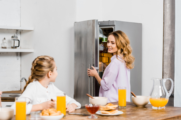 Mother reaching into the fridge to grab food