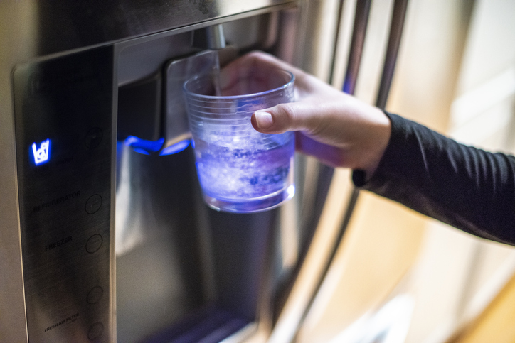 filling up a glass from fridge water dispenser