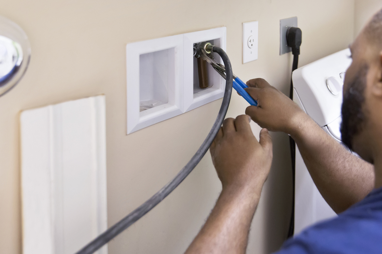 a man connects a laundry appliance into the wall