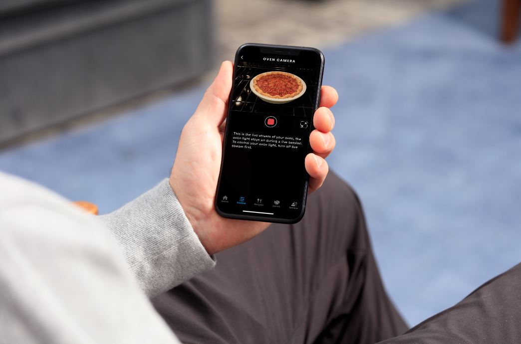 checking pie baking in the oven while on smartphone 