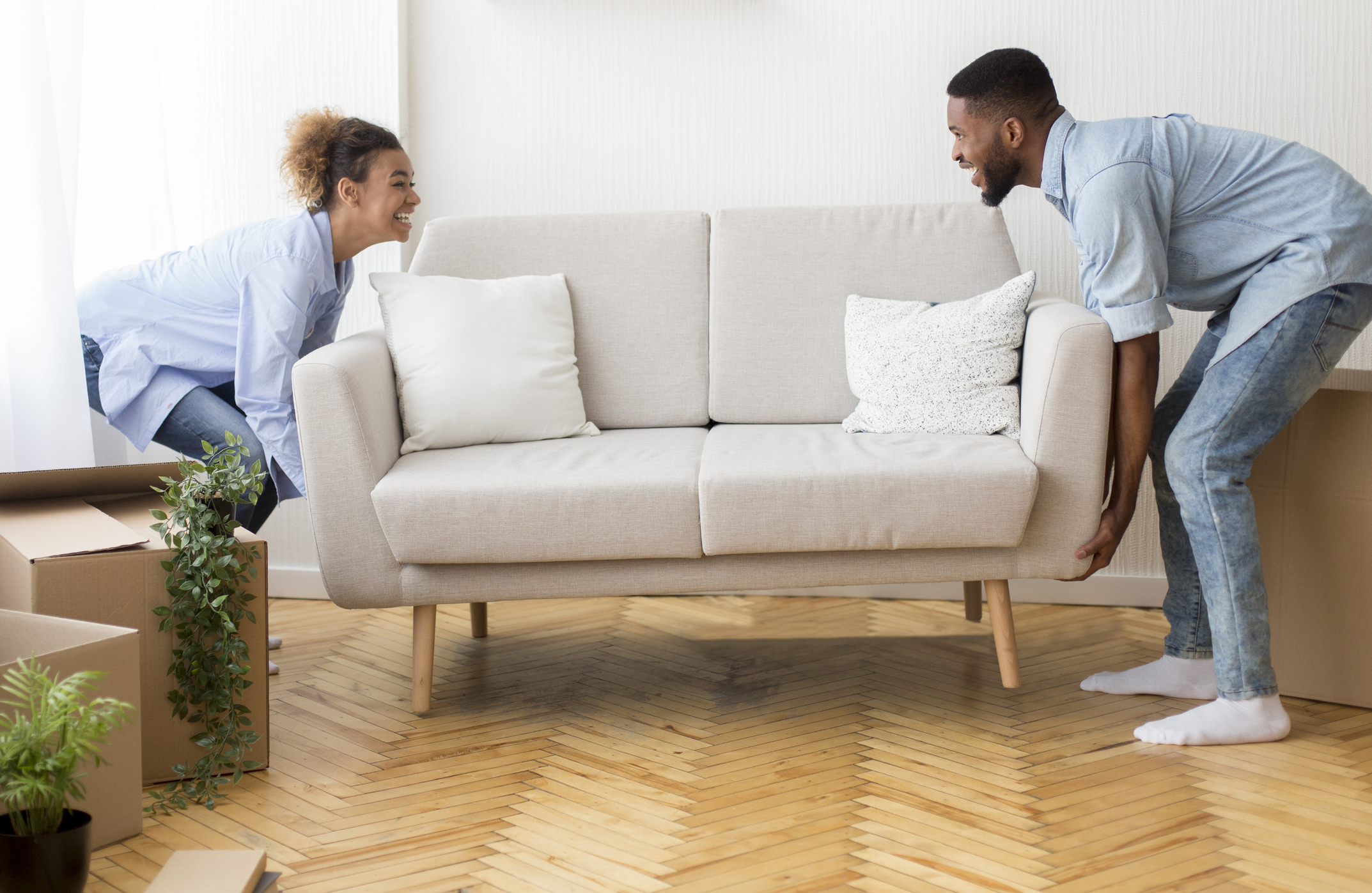 couple moving new couch into their home