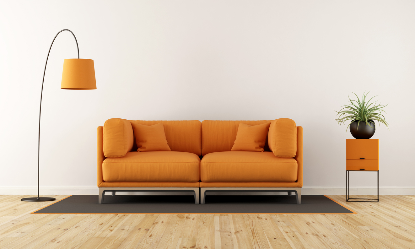 orange couch in the center of matching lamp and side table 